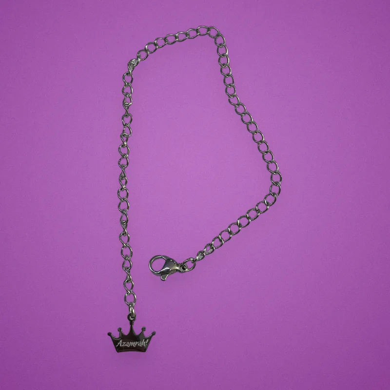 Silver chain bracelet with a crown charm engraved 'Azamrah!'